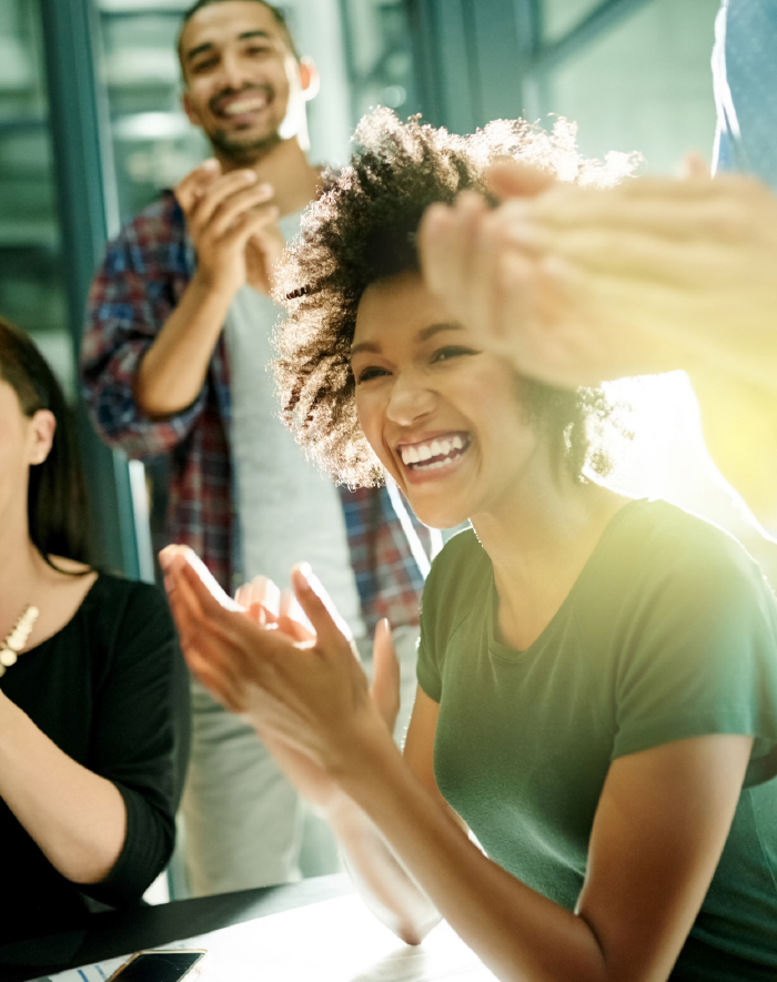 Lachende Kollegen im Büro applaudieren